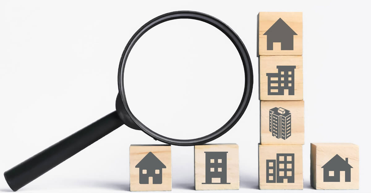 property icons on wooden cubes with magnifying glass